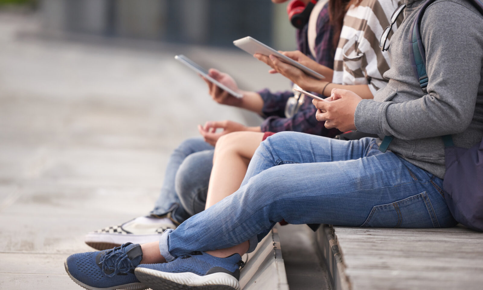 Tinejdžeri sjede na klupici i gledaju u mobitele