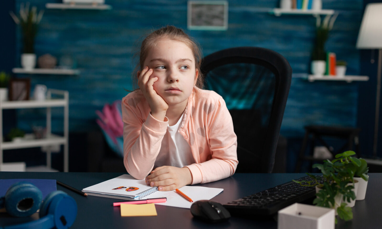 Djevojčica sjedi za stolom i dosađuje se