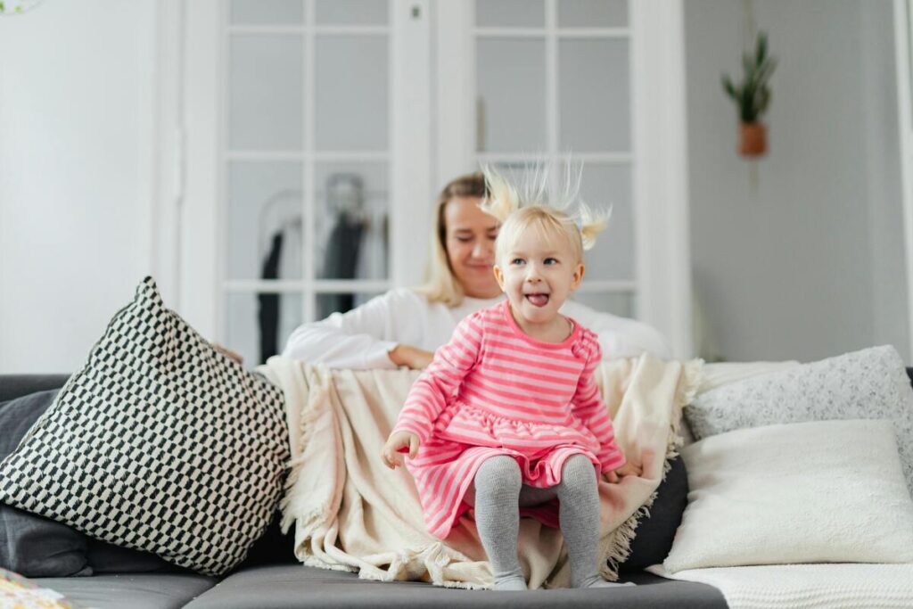 Djevojčica skače po kauču dok majka posprema