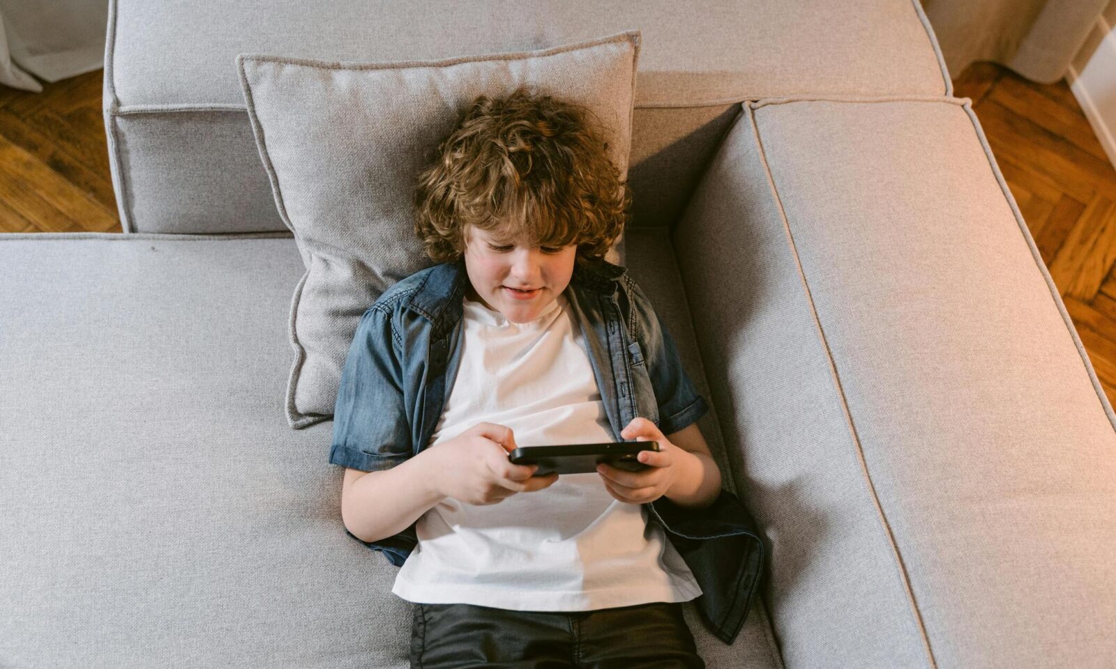 Dječak na kauču gleda sadržaj na mobitelu