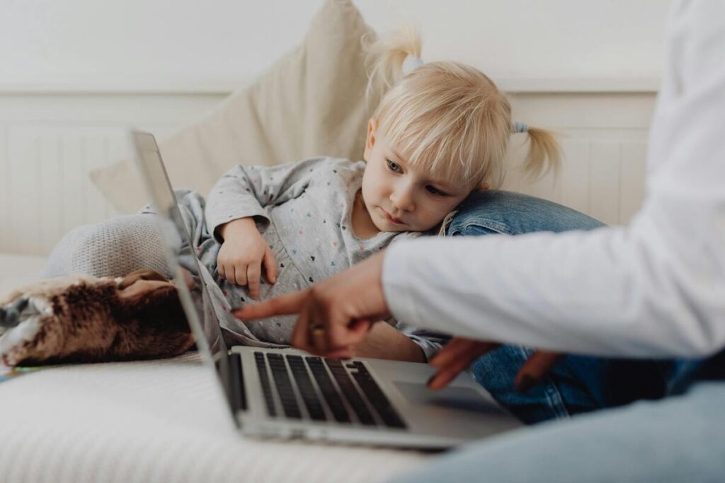Djevojčica na kauču gleda što njena majka radi na laptopu