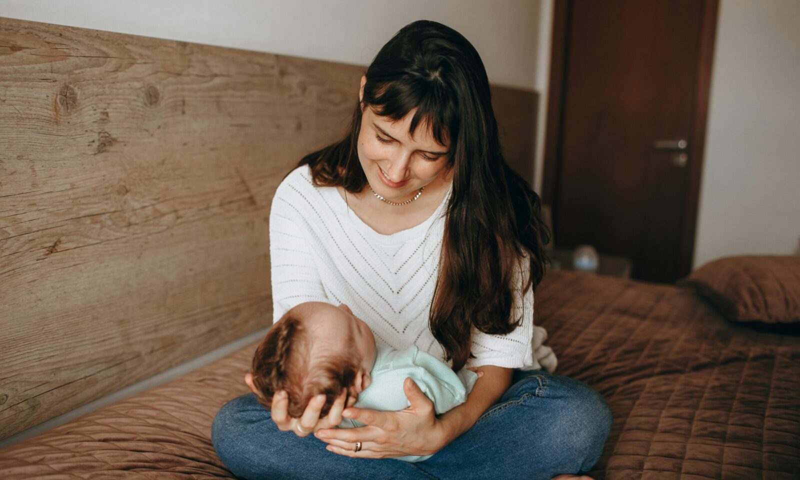 Majka na krevetu drži novorođenče