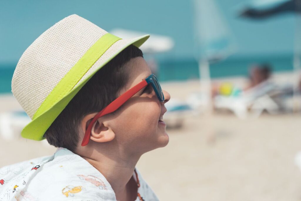Dječak sa sunčanim naočalama i šeširom na plaži