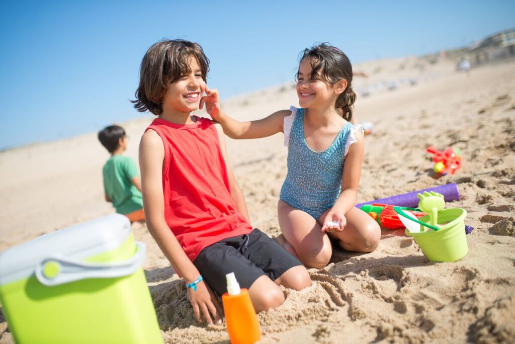 Djeca se na plaži mažu kremom za sunčanje