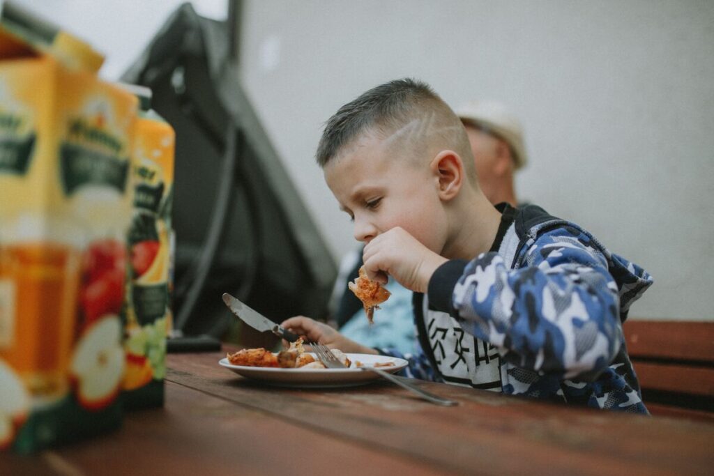 Dječak jede za kuhinjskim stolom