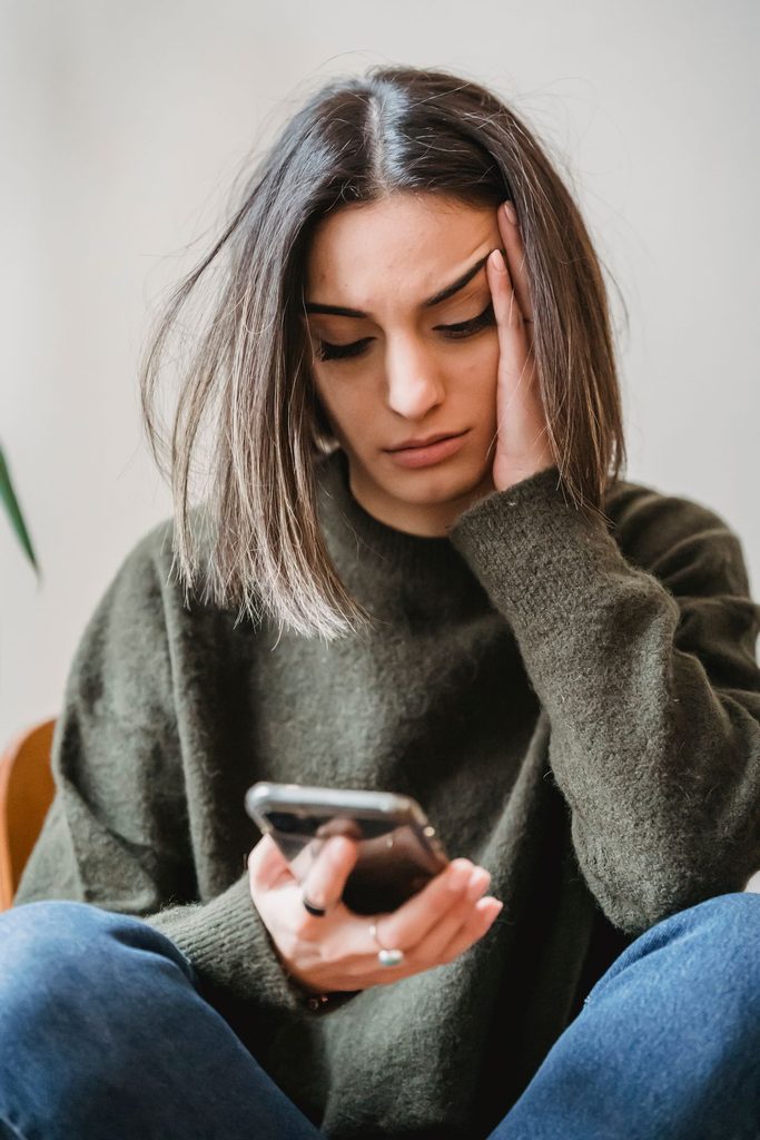 Zabrinuta žena gleda u mobitel